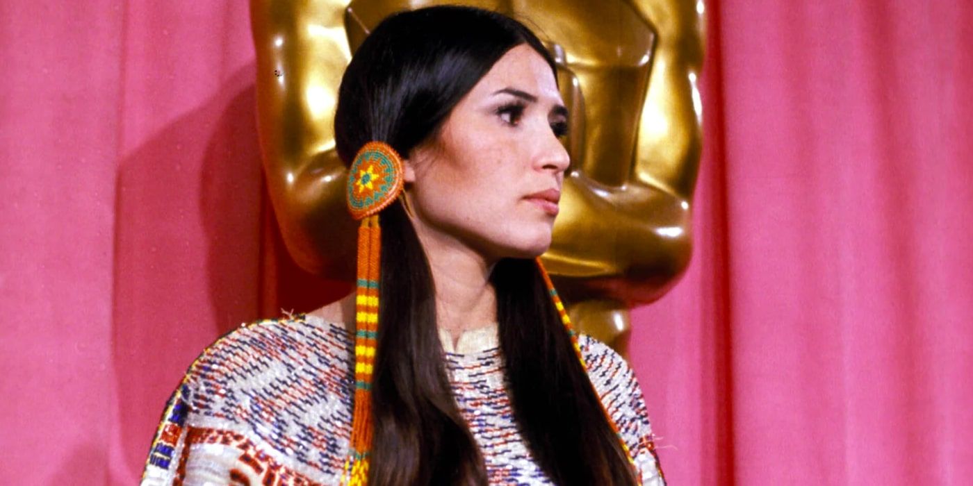 Sacheen Littlefeather is stood in front of a large Oscar statue