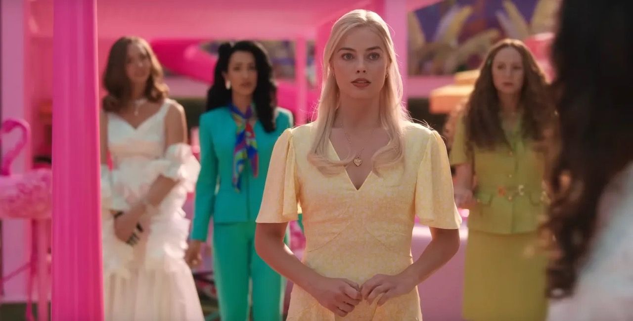 Barbie stands in her yellow dress surrounded by her fellow Barbies -1