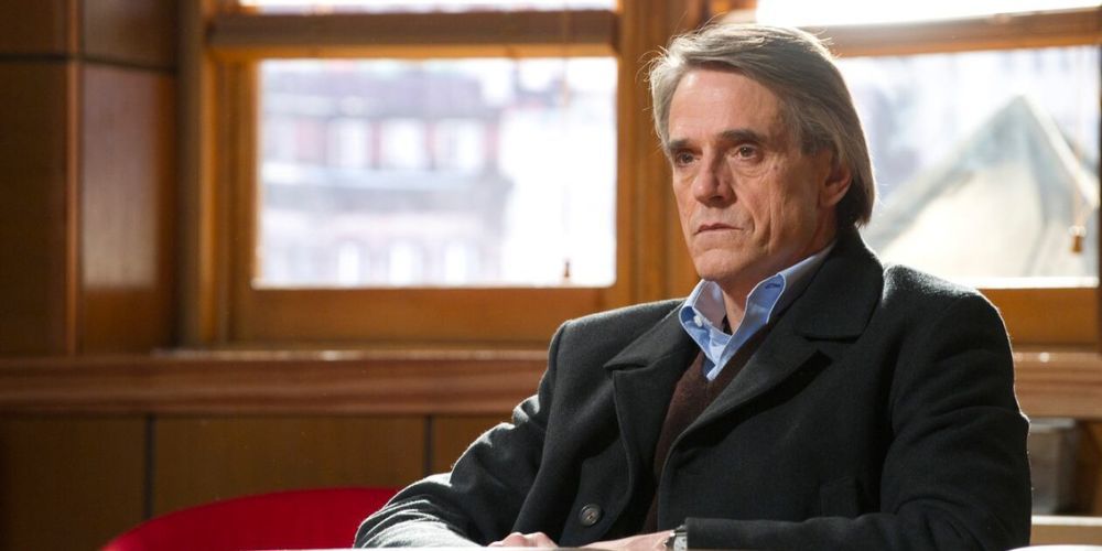 Jeremy Irons como Capitão Jackson sentado em frente às janelas em Law & Order: SVU.