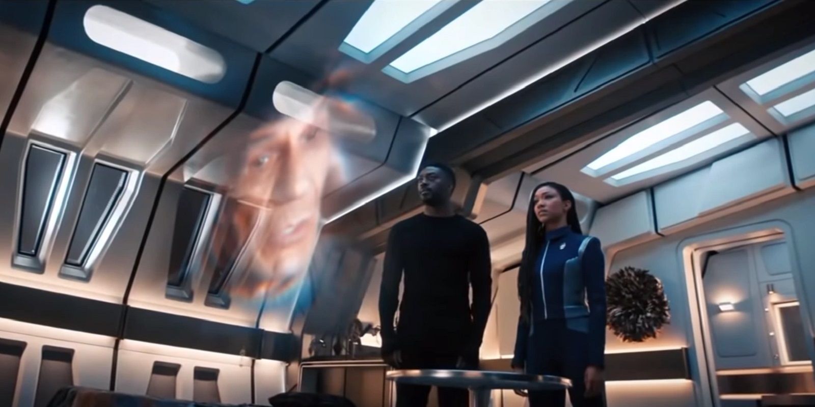 Michael Burnham and Cleveland Booker looking at a holographic image of Spock from TNG on Star Trek Discovery