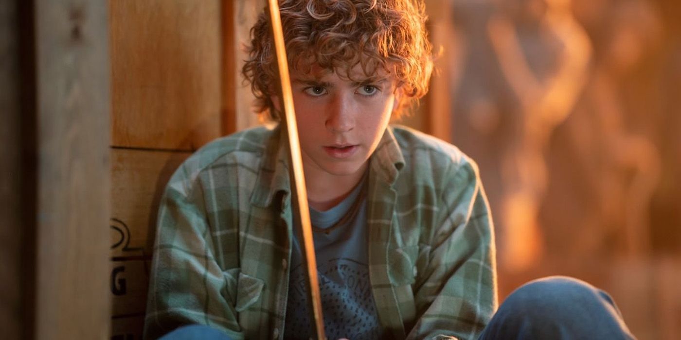 Percy Jackson (actor Walter Scobell) crouches in a plaid shirt in Percy Jackson and the Olympians