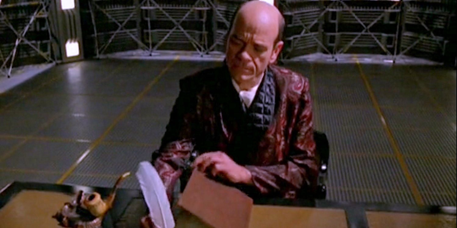 The Doctor sitting a desk in a smoking jacket and writing with a quill pen from Star Trek Voyager