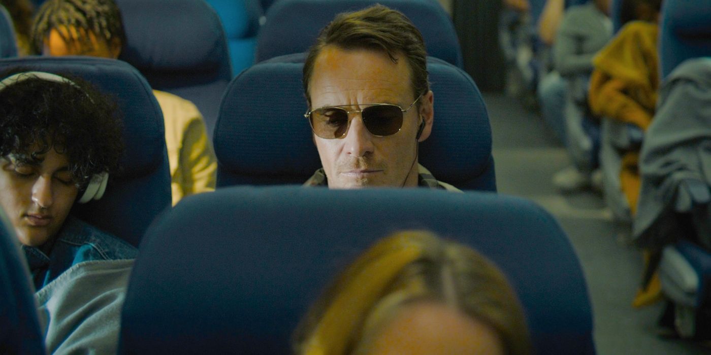 Michael Fassbender sits in an airplane in The Killer
