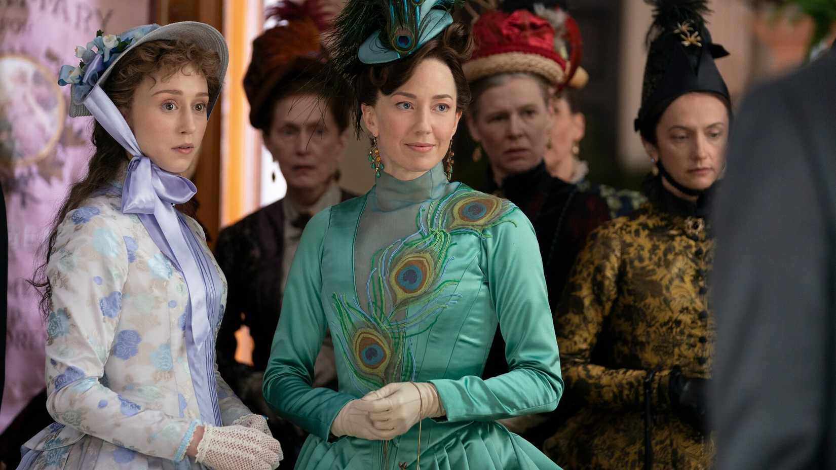 Gladys and Bertha Russell surrounded by stern-looking women in The Gilded Age Season 1.