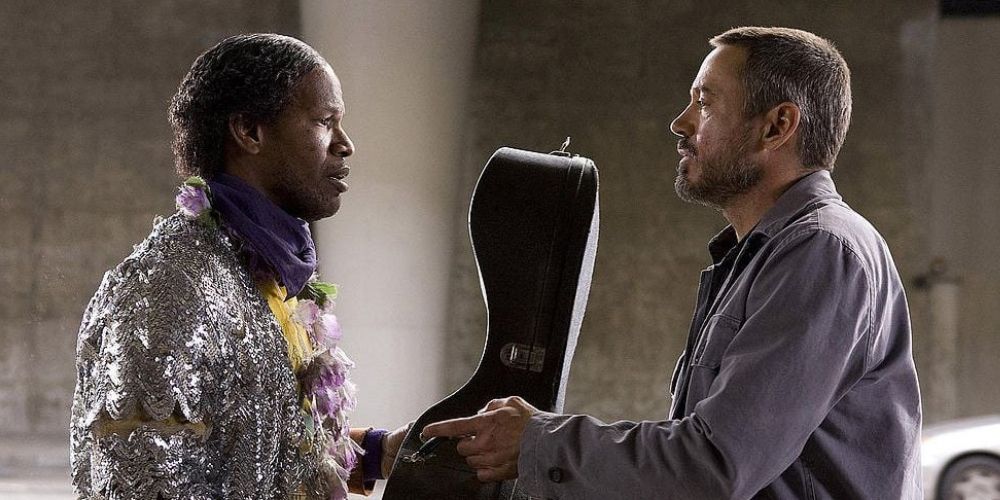 Jamie Foxx as Nathaniel Ayers and Robert Downey Jr. as Steve Lopez hold a cello between them in The Soloist