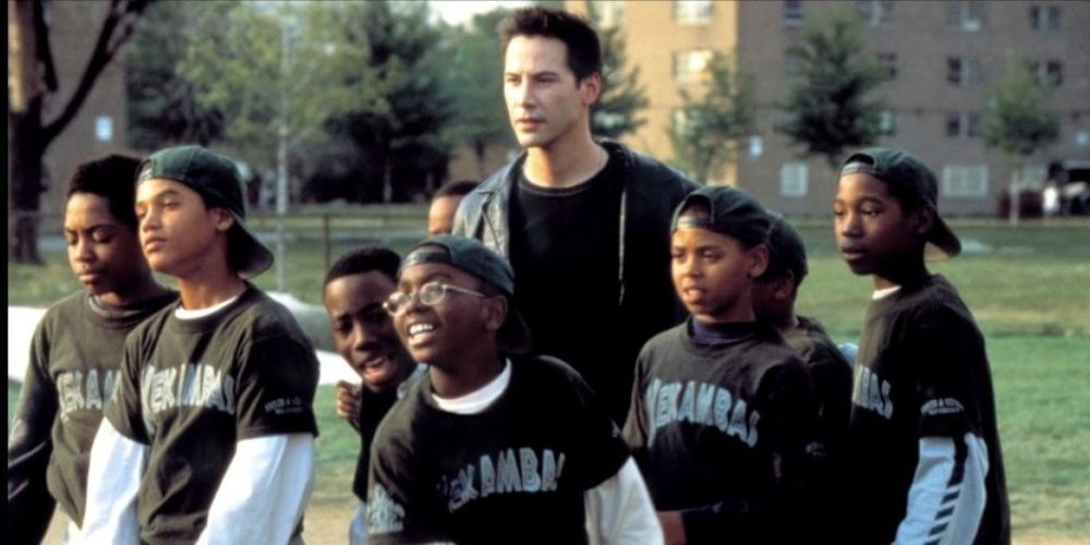 Keanu Reeves as Conor O'Neill stands behind a little league team made up of Black boys in Hardball