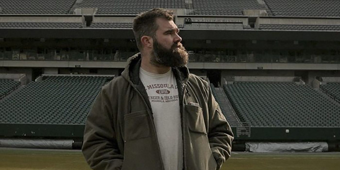 Jason Kelce standing on a football field in an empty stadium, looking to the side in a scene from the douseries Kelce.
