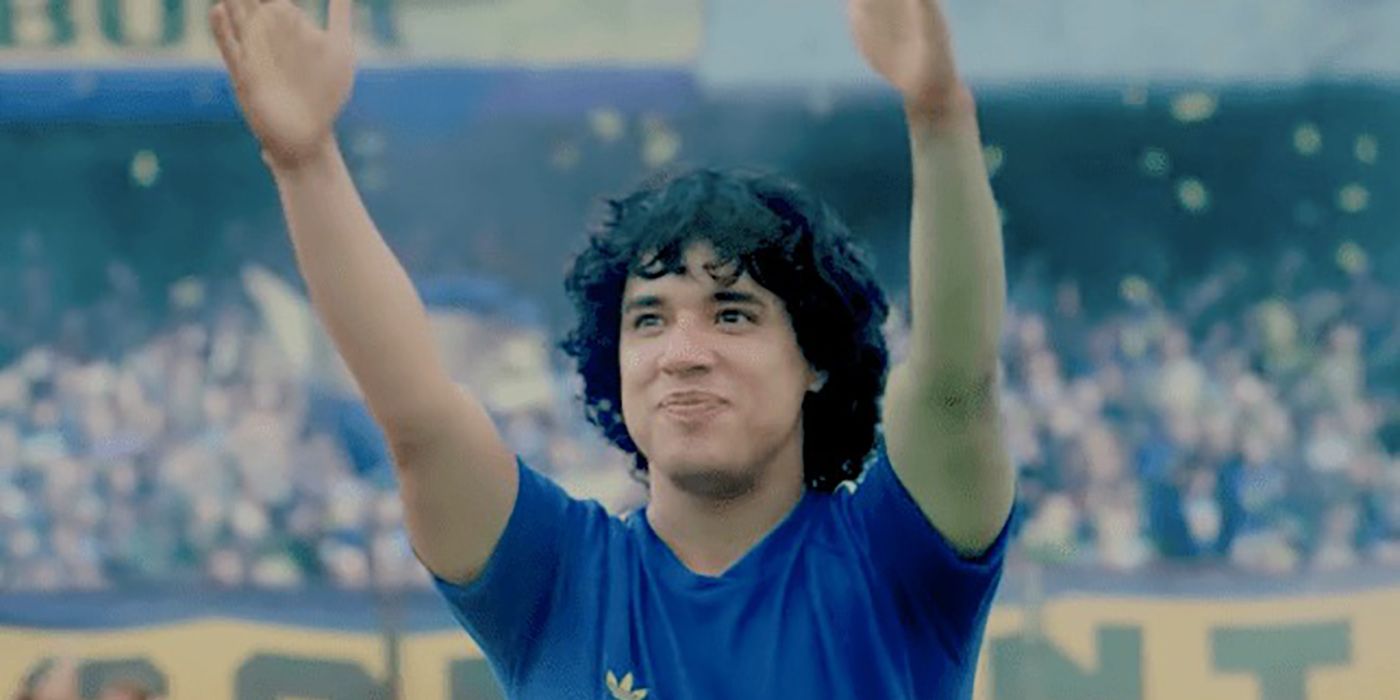 A young man as Diego Maradona raising his hands in the air on the football field in a scene from Maradona: Blessed Dream.