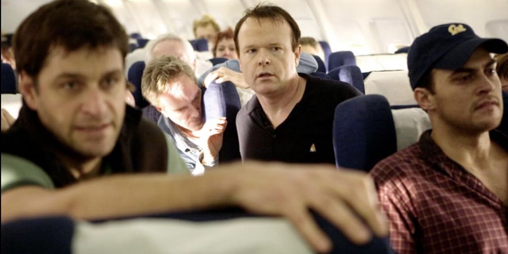 Peter Hermann as Jeremy Glick, Christian Clemenson as Thomas E. Burnett, Jr., and Cheyenne Jackson as Mark Bingham sit at the front of a group of passengers on a plane in United 93