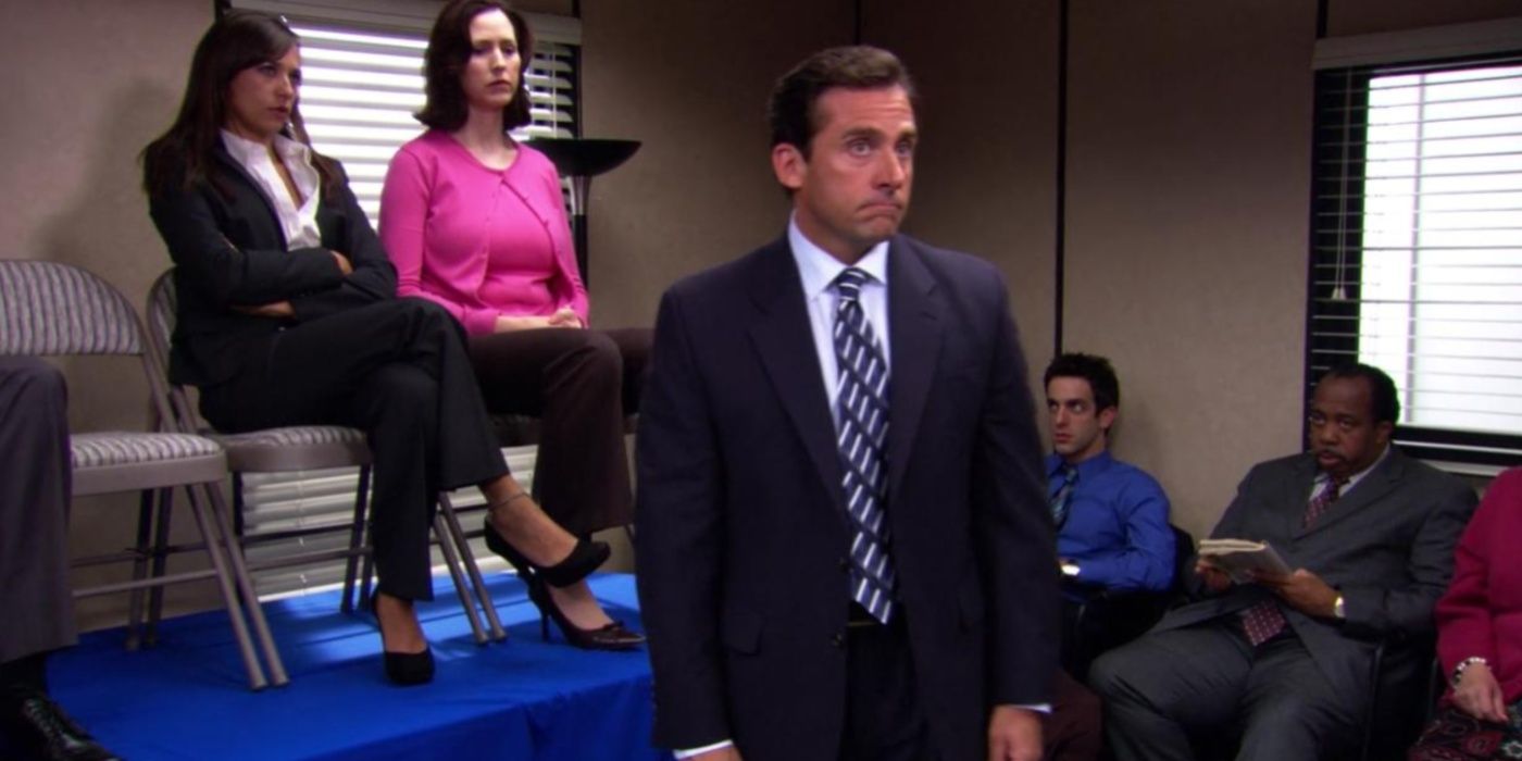 Michael standing in front of new employees from the Stamford branch who are sat on a table in The Office