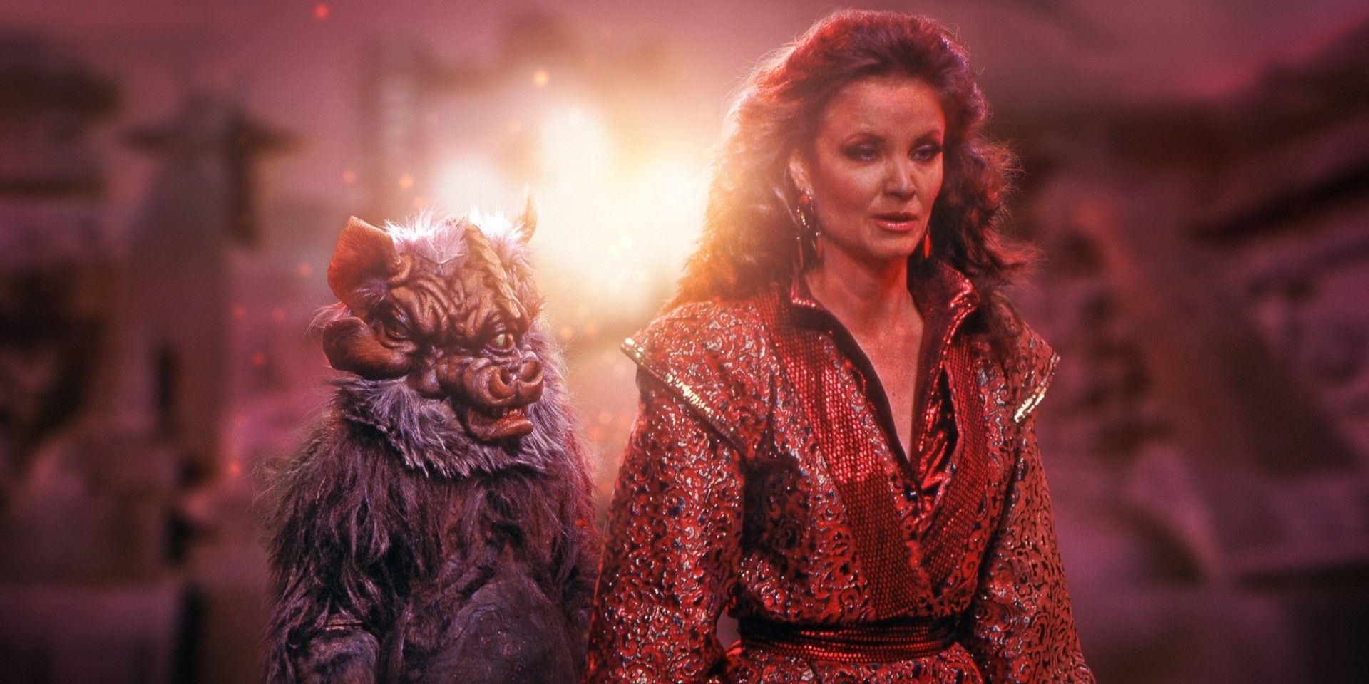 A Tetrap standing behind the Rani (Kate O'Mara) against a blurry red background in Doctor Who.