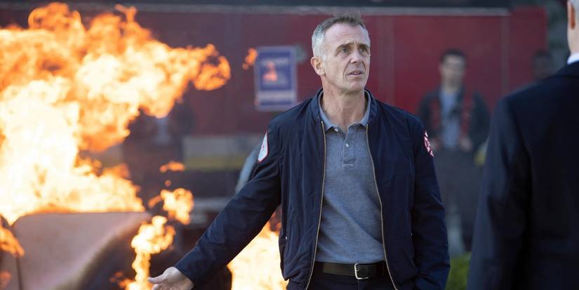 David Eigenberg as Christopher Herrmann stands in front of a burning couch on Chicago Fire