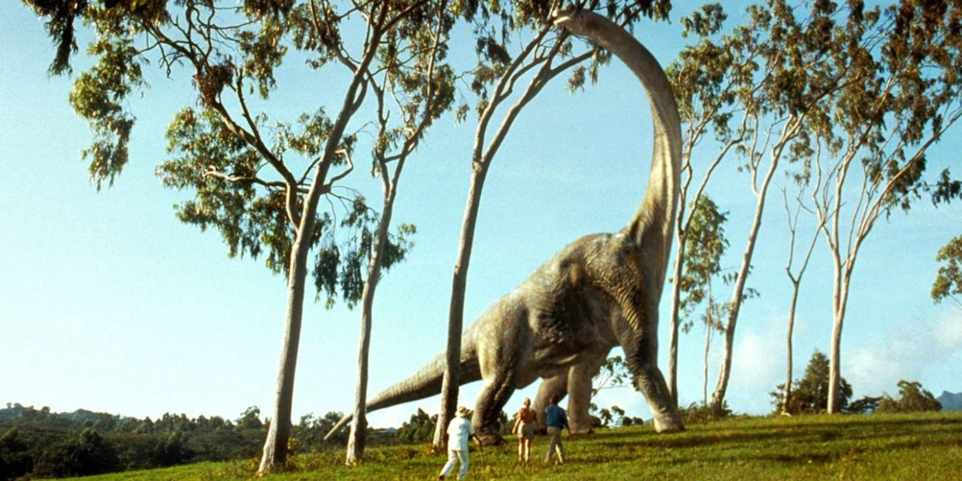 John Hammond, Ellie Satler e Alan Grant olhando para um Braquiossauro em Jurassic Park.
