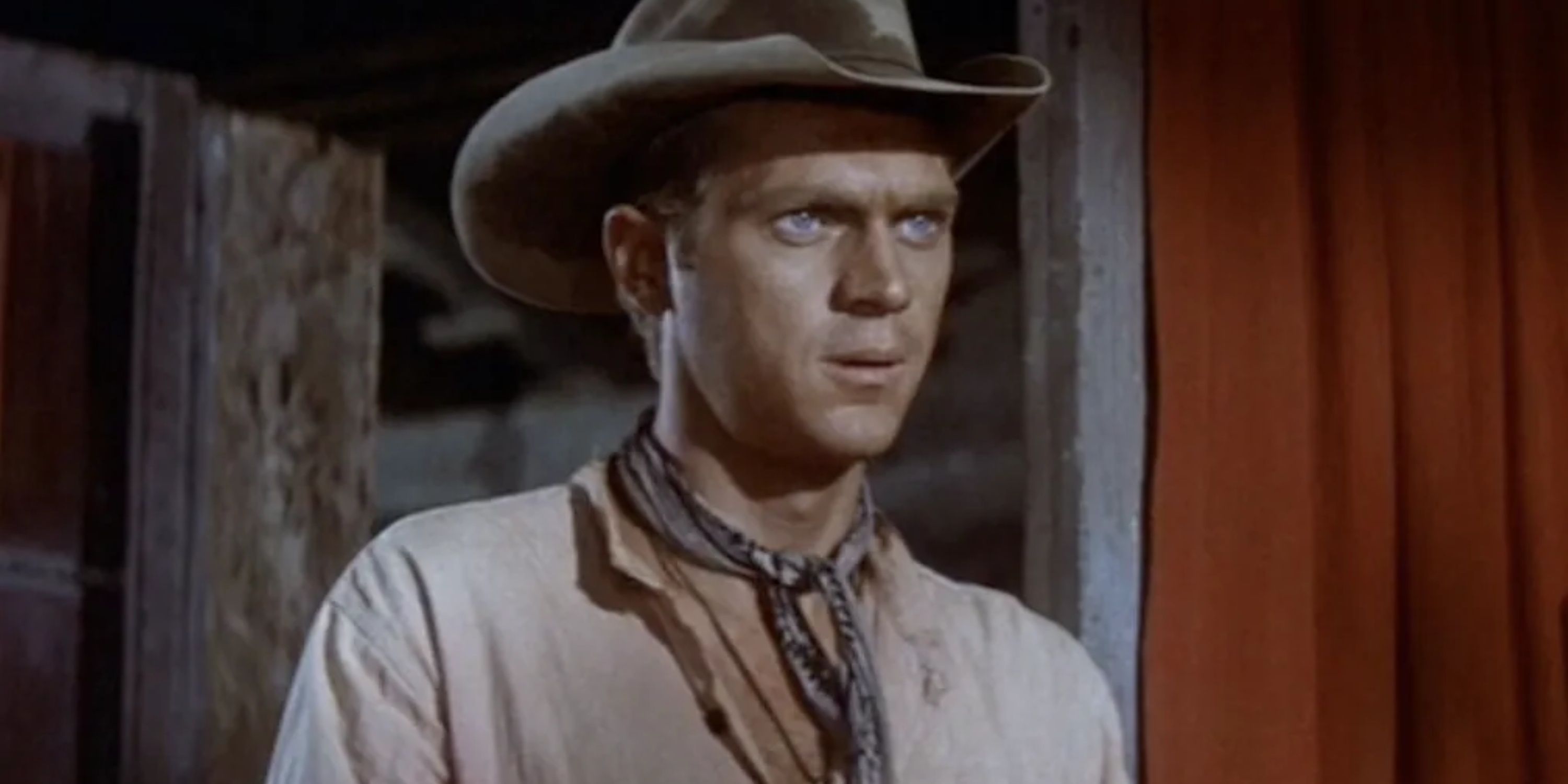 Vin Tanner played by Steve McQueen stands in a doorway in The Magnificent Seven