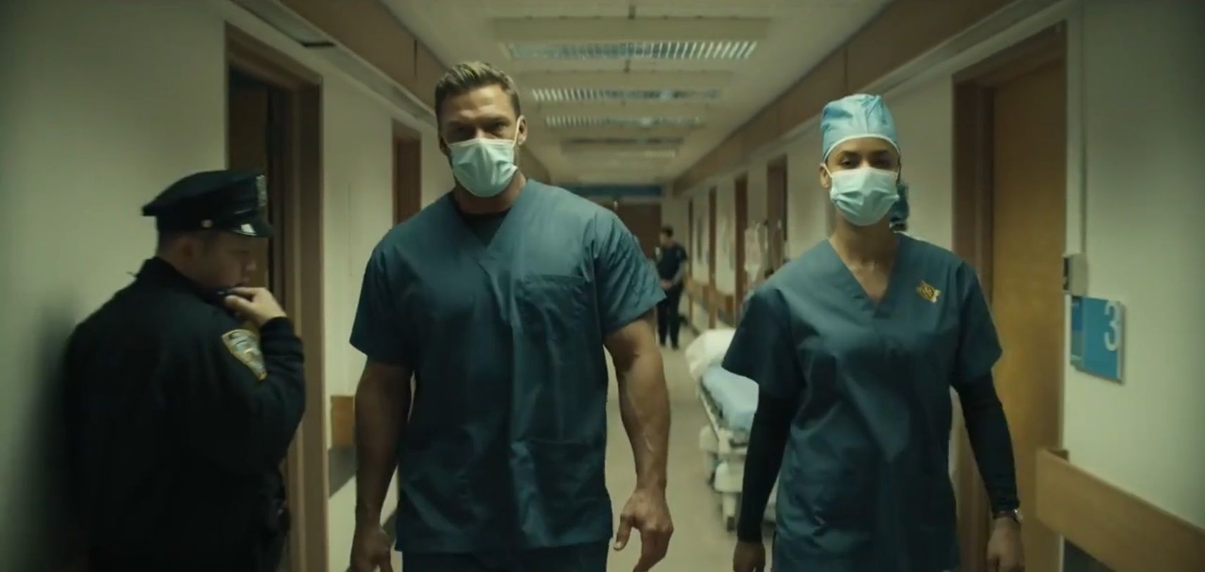 Reacher and Neagley disgused in scrubs and masks walking past a cop in a hospital from Season 2