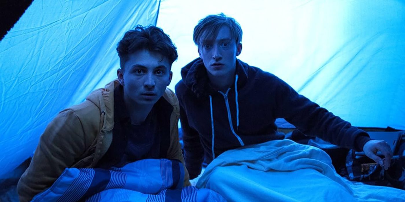 Two men in a tent looking terrified, dark blue light around them in a scene from True Horror.