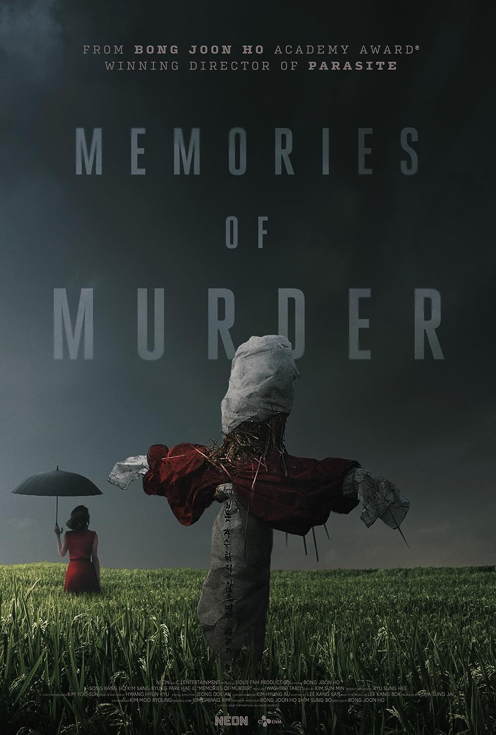 Um Espantalho e uma mulher com um guarda-chuva em um campo no pôster Memórias de Assassinato