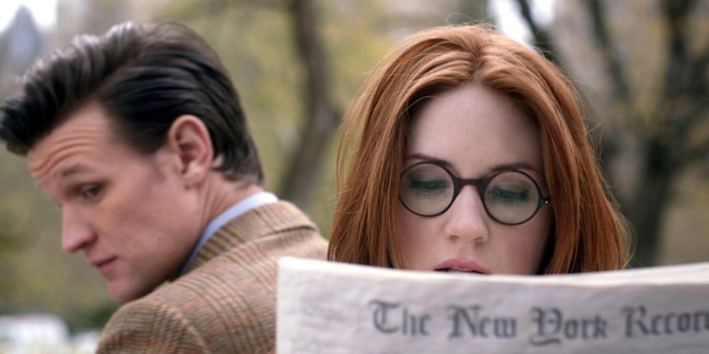 Amy Pond reads a newspaper with the Eleventh Doctor in the background in Doctor Who