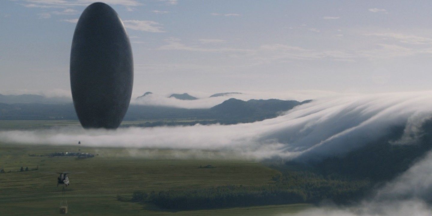 The oblong alien spaceship called the Shell hovers over the green and foggy landscape in Arrival.