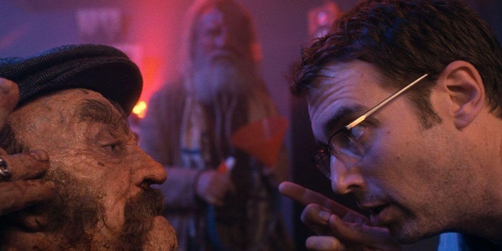 William (played by Jonah Ray) talks to the undead severed head of Vlad (played by Alex Winter).