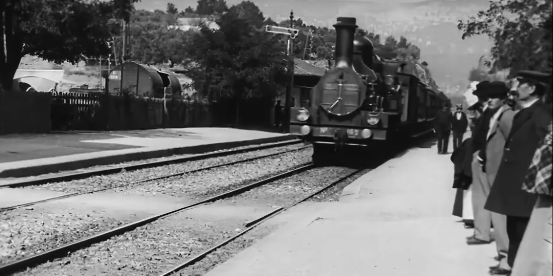 A black and white still shows the train pulling up to its stop in The Arrival of a Train at La Ciotat