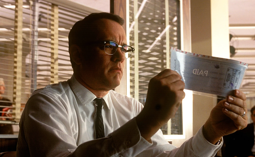 Tom Hanks examines a check in Catch Me If You Can.