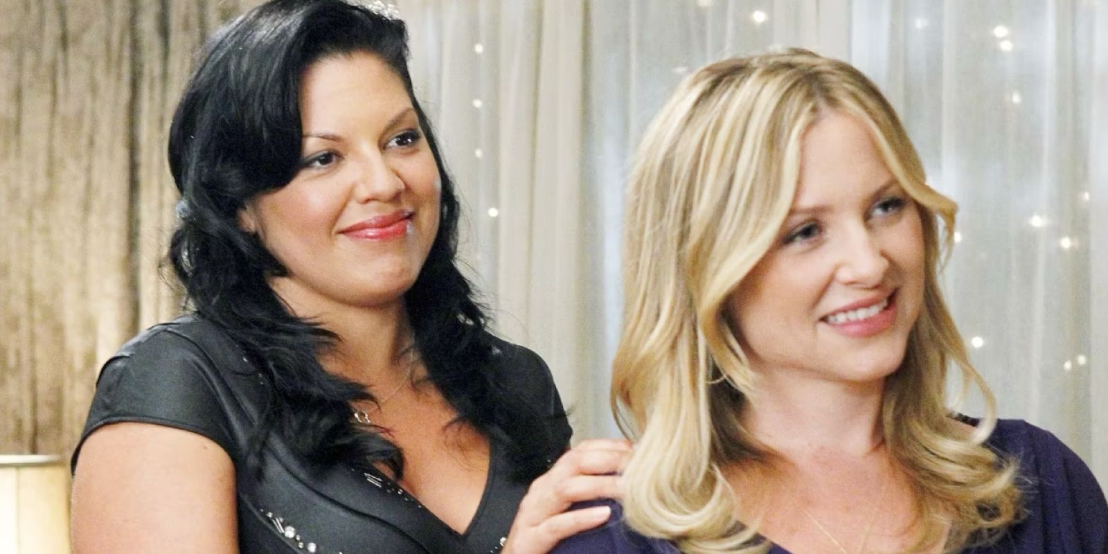 Callie pone su mano sobre el hombro de Arizona mientras ambas sonríen ante algo en Grey's Anatomy.