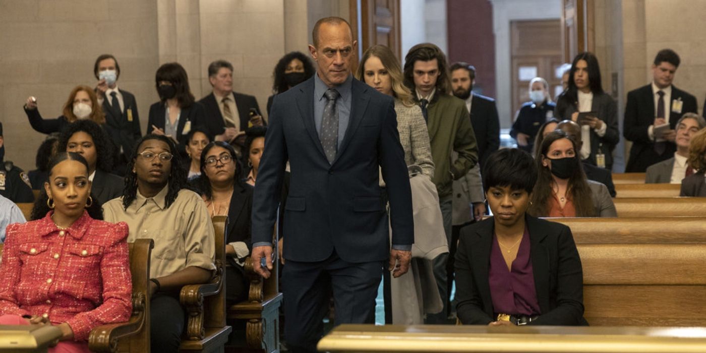 Christopher Meloni as Elliot Stabler walks into a courtroom; behind him is Allison Siko as Kathleen Stabler and Nicky Torchia as Eli Stabler; Danielle Moné Truitt as Ayanna Bell sits in the front row of the court room on Law & Order_