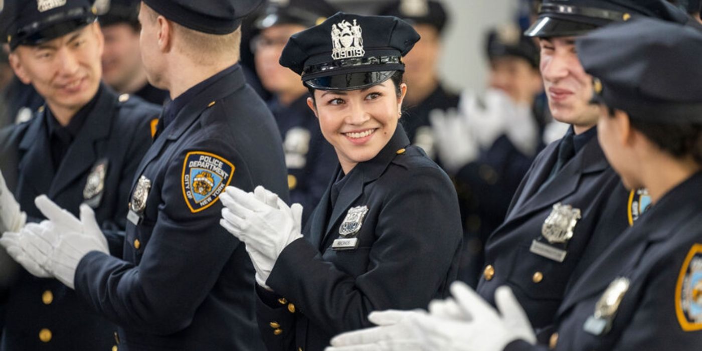 Dani Montalvo as Maria Recinos stands in her dress blues surrounded by other police officers in their dress blues on Law & Order_ SVU