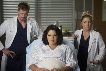 Arizona and Mark standing behind a gowned Callie during an OB appointment in Grey's Anatomy