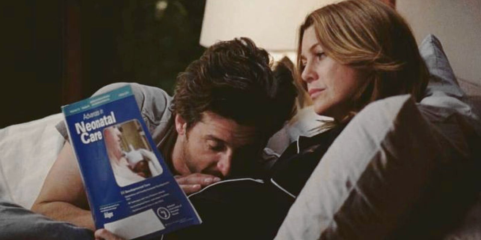 Derek kissing Meredith's pregnant belly as she reads in bed in Grey's Anatomy.