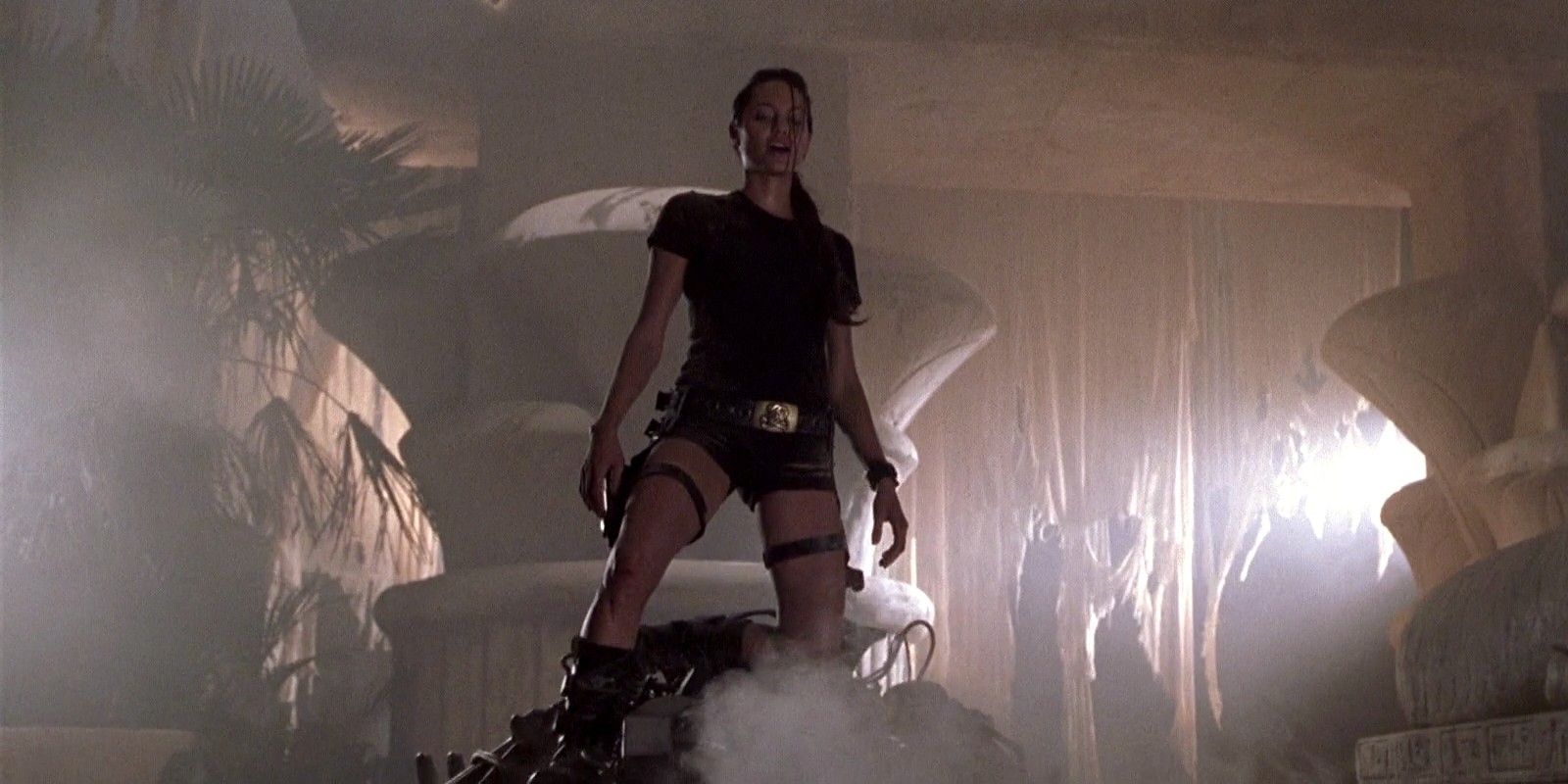 Lara Croft fica triunfante sobre robôs destruídos durante um exercício de treinamento no filme Lara Croft Tomb Raider