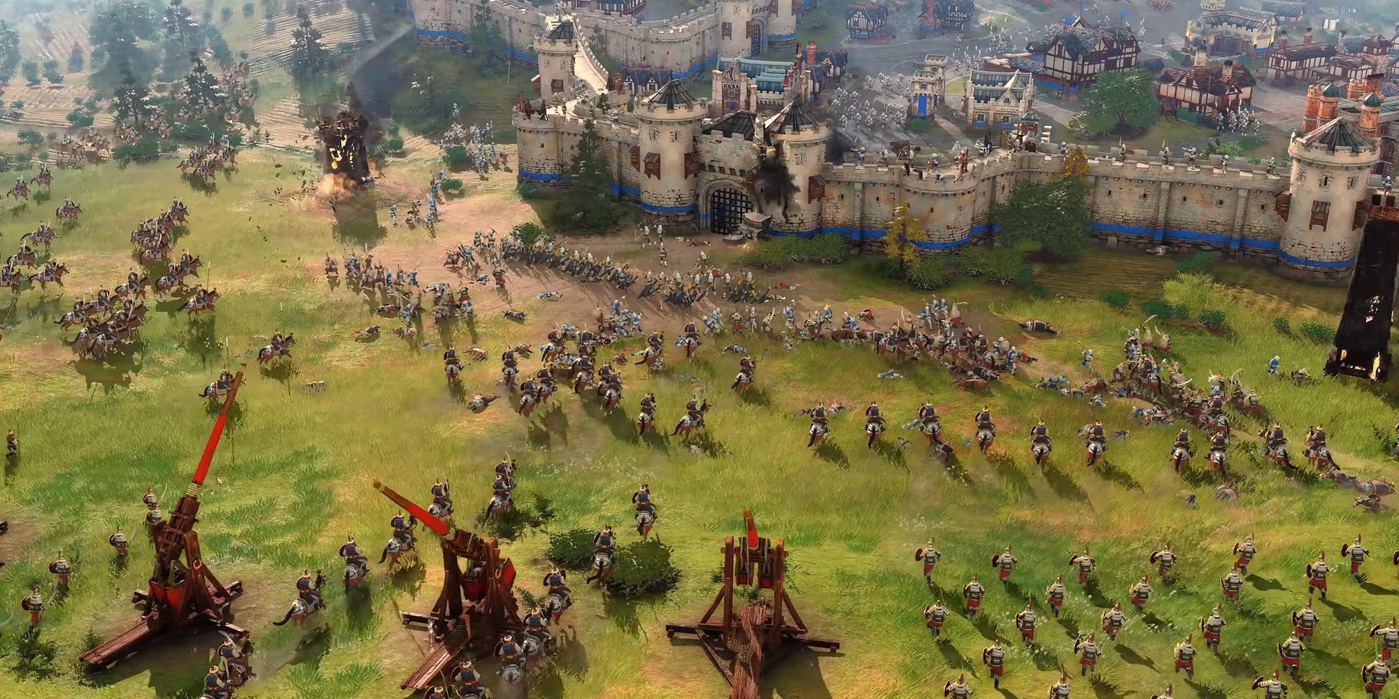 A massive siege is taking place in front of a fortified wall surrounding a castle village in Age of Empires IV