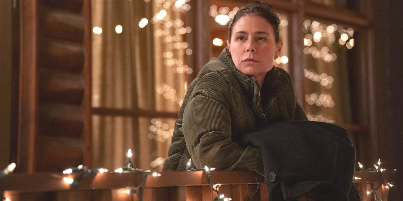 Grace Poe (actor Maura Tierney) leans on a rail outside her cabin in a brown coat in American Rust