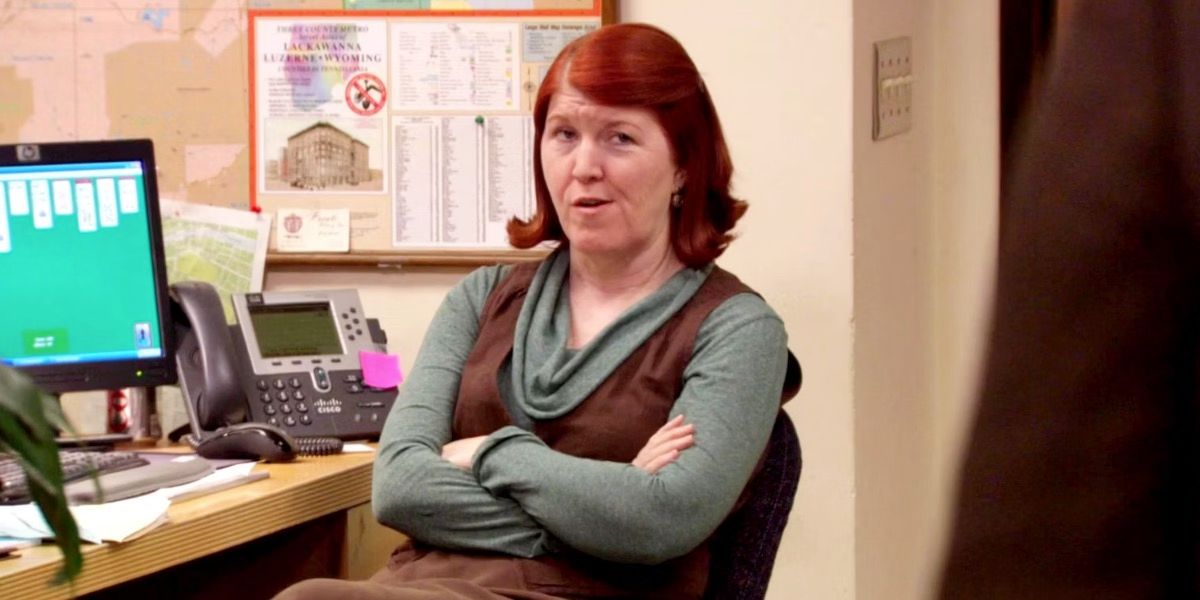 Meredith at her workstation with folded arms and a cheeky grin