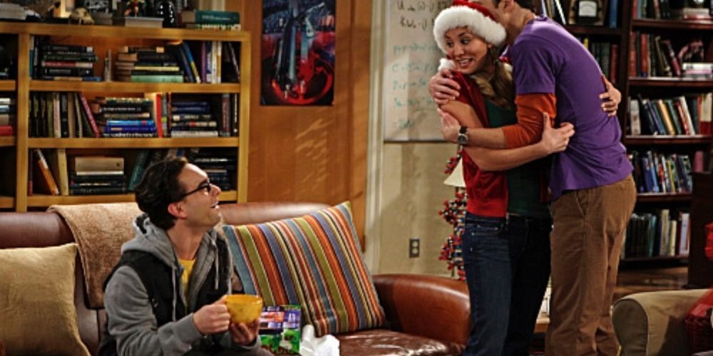 Sheldon abraça Penny enquanto ela sorri para Leonard em The Big Bang Theory.