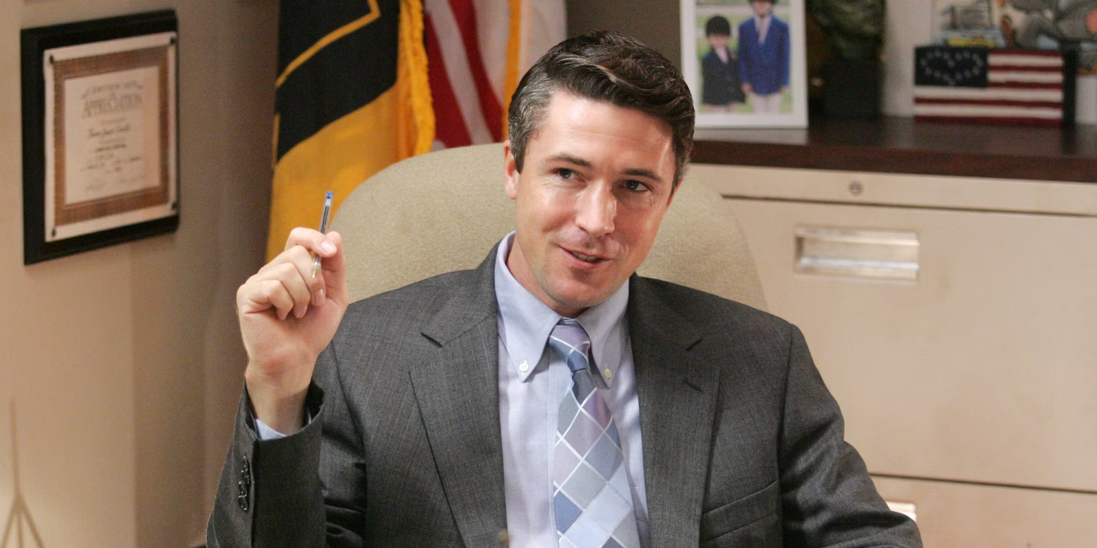 Tommy Carcetti sitting down holding a pen in The Wire 