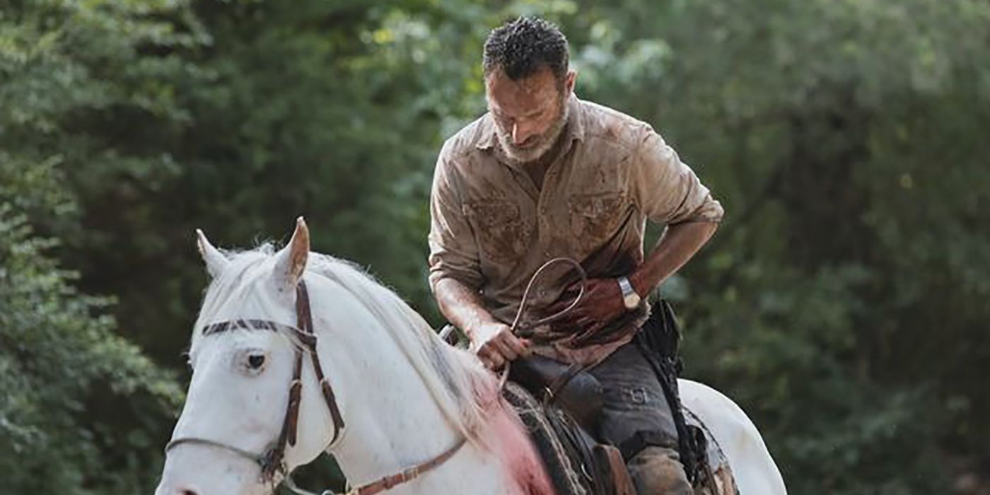 Rick bleeding from the torso, holding his stomach and keeled over on a horse on The Walking Dead.