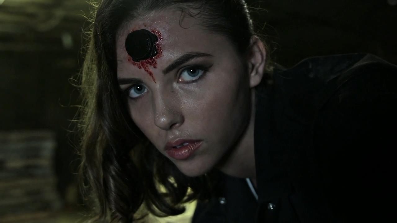 A woman with a bloody device carved in her forehead in Headgame