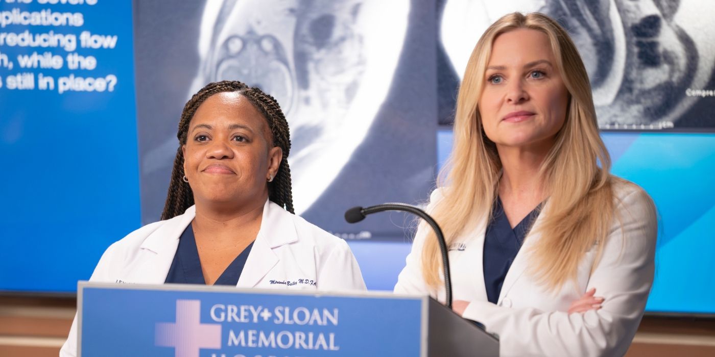 Chandra Wilson as Miranda Bailey stands next to Jessica Capshaw as Arizona Robbins behind a Grey-Sloan Memorial Hospital podium on Grey's Anatomy