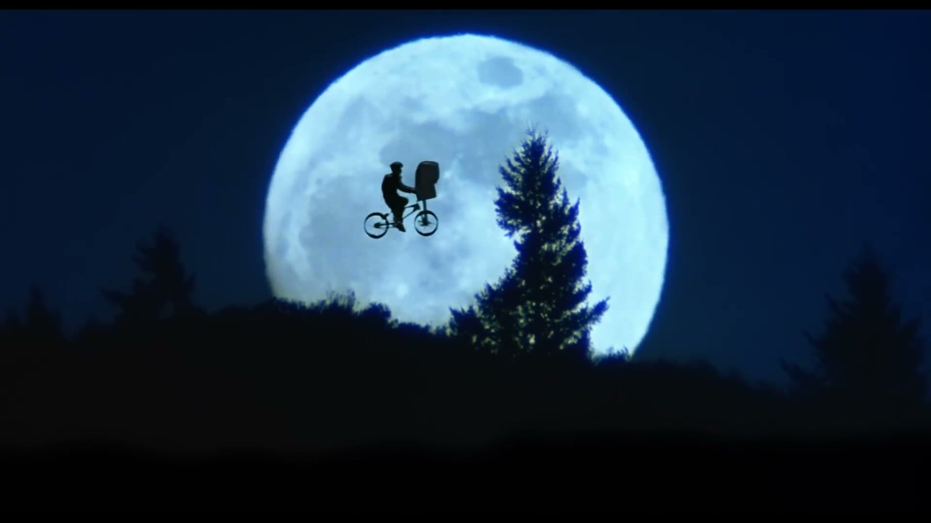 Elliot and E.T. silhouttes as they fly across the moon on a bike