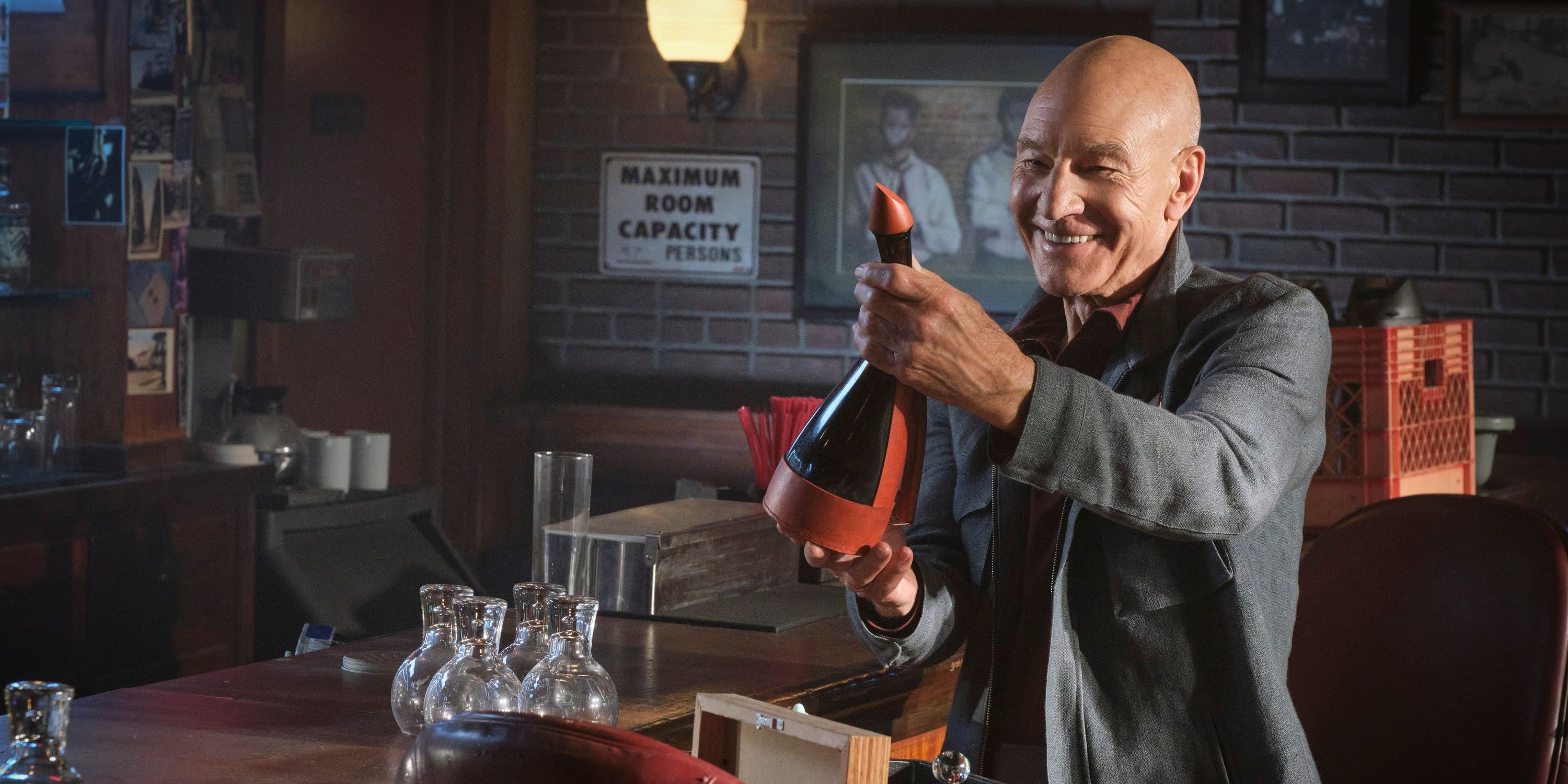 Jean-Luc holds up a bottle of space booze to young Guinan (off screen) in Star Trek Picard