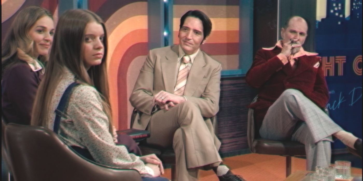 Jack Delroy (actor David Dastmalchian) sits between his guests in movie Late Night with the Devil
