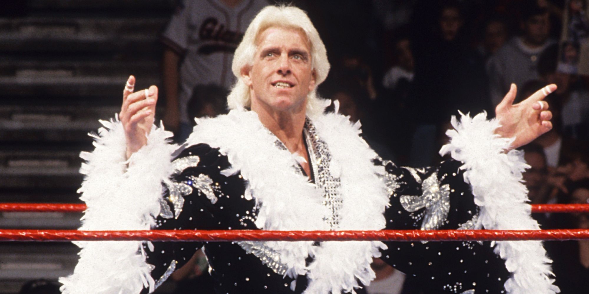 Nature Boy Ric Flair vestindo seu manto icônico e fazendo sua entrada em um evento de luta livre