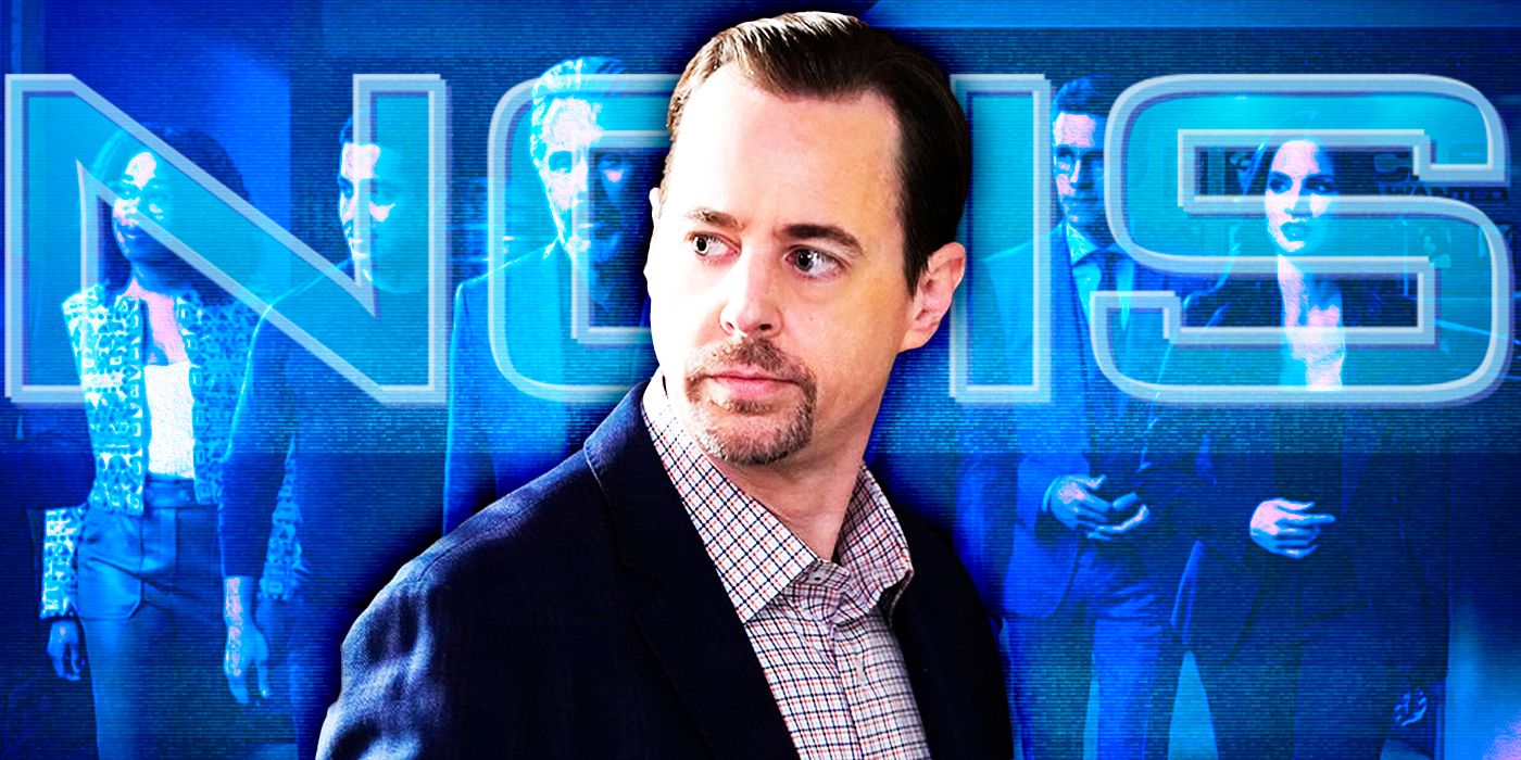 Tim McGee (actor Sean Murray) in a blue suit in front of the NCIS logo