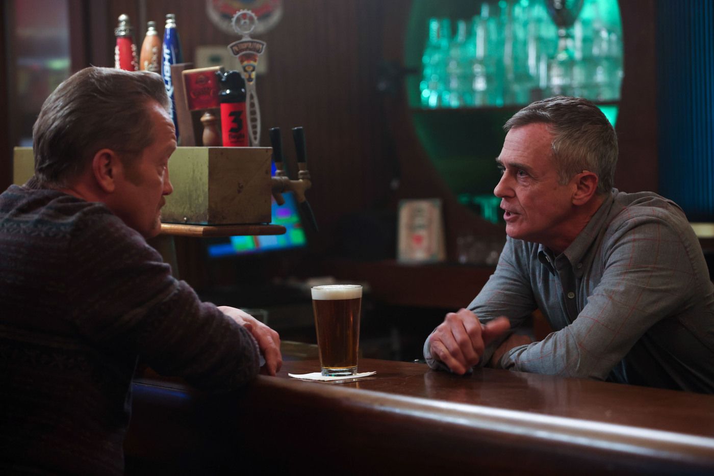 Herrmann (actor David Eigenberg) leans behind the bar at Molly's talking to Mouch on Chicago Fire