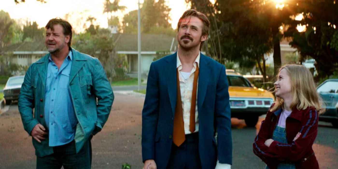 Ryan Gosling, Russell Crowe e Angourie Rice estão do lado de fora, na rua, sorrindo.