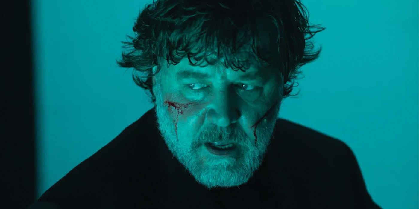A blue-tinted image from The Exorcism featuring a bearded actor, played by Russell Crowe, with two cuts on his cheeks.