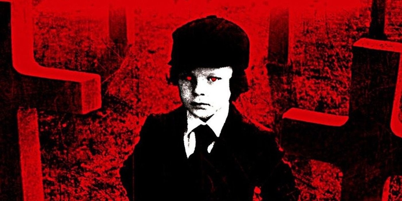 The five year old Anti-Christ, Damien Thorne, standing ominously in a graveyard filled with crosses, his eyes and the background red.