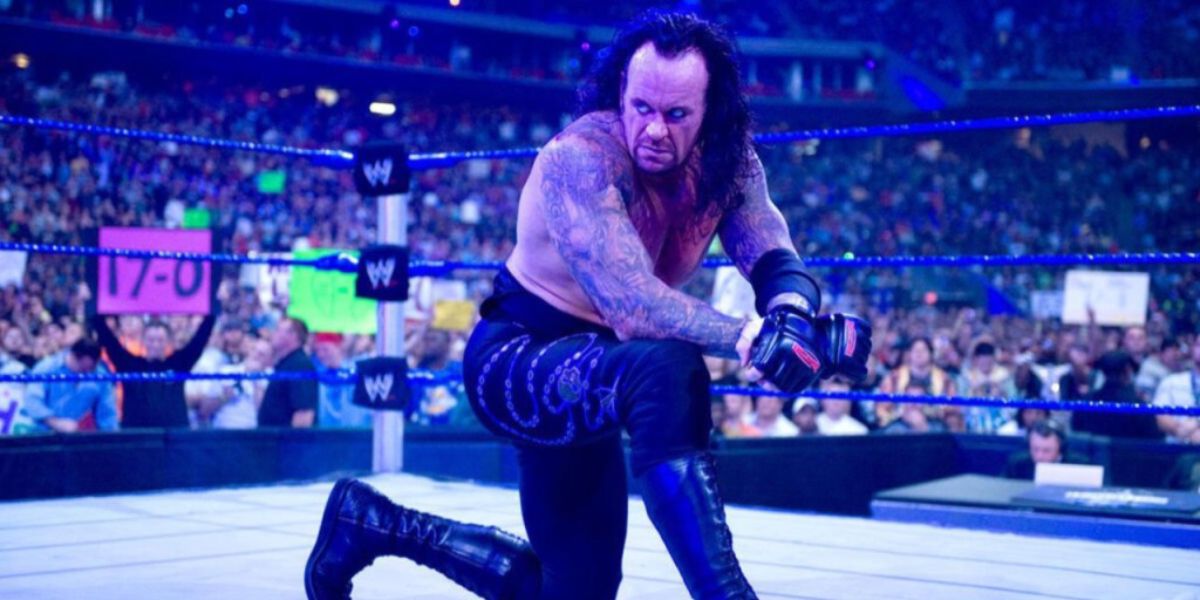 The Undertaker ajoelhado sob luzes azuis após sua vitória na WrestleMania 25